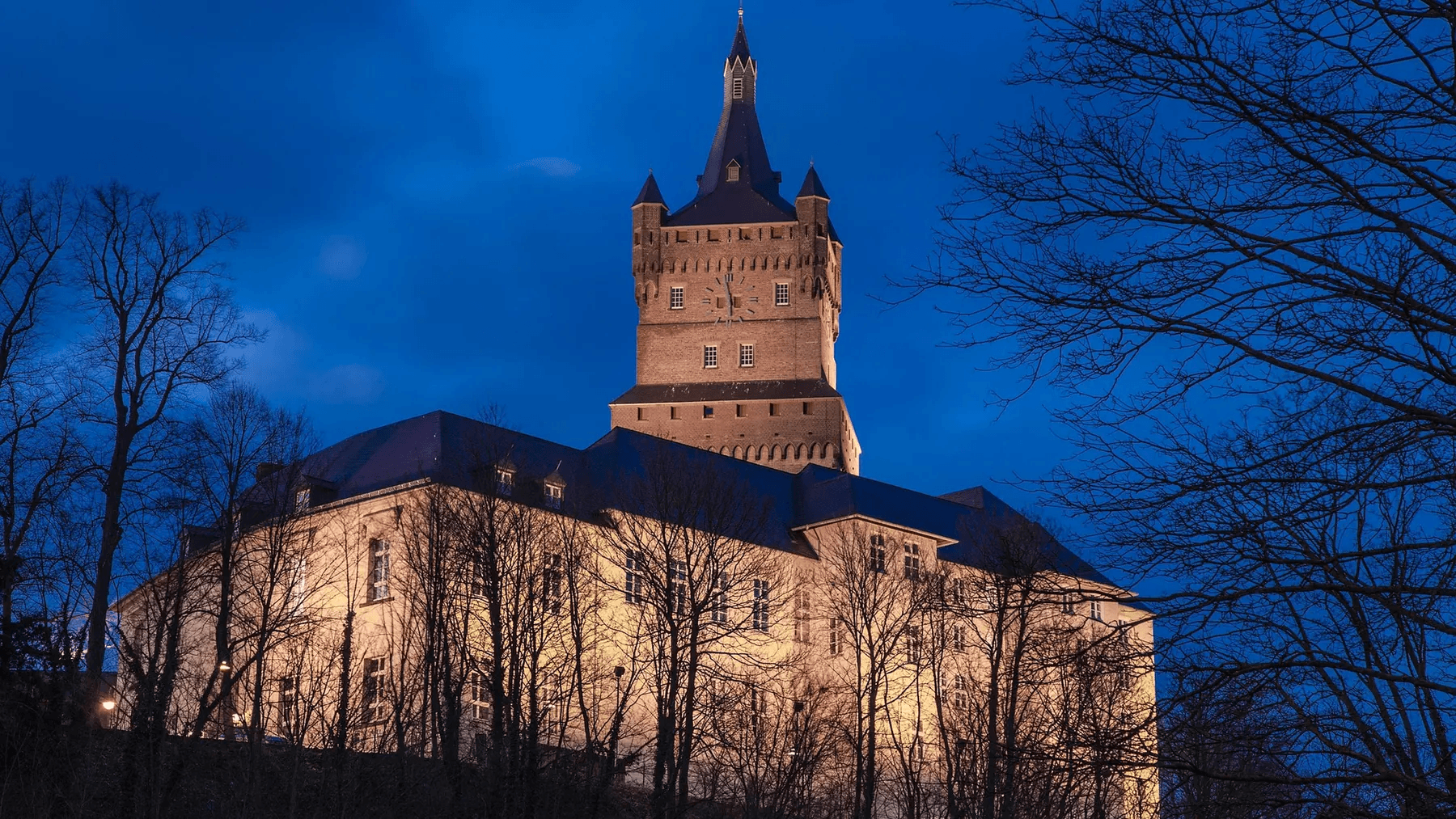 Die Schwanenburg in Kleve am Abend, angestrahlt vor dunkelblauem Himmel